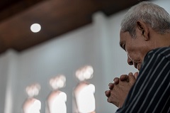 Ein Mann betet beim Sonntagsgottesdienst