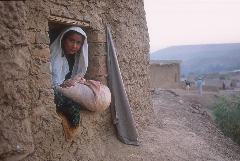 An ethnic Uzbek refugee girl from Afghanistan looks out the window of her family's mud-walled house In the Shamshatoo refugee camp near Peshawar, Pakistan.