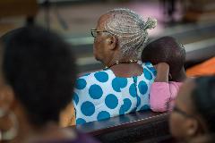 A young girl lays her hand on a relative's shoulder as Sunday service gathers several hundred congregants in the Moshi Lutheran Cathedral, in the Evangelical Lutheran Church in Tanzania’s northern diocese, March 2022.