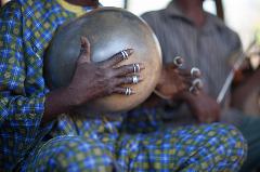 Men play a gourd percussion instrument with several rings on each finger, Senegal.