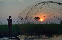 A boy throws a fishing net at dawn in the village of Phar Thruey in northern Cambodia.