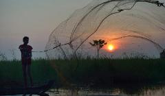 A boy throws a fishing net at dawn in the village of Phar Thruey in northern Cambodia.